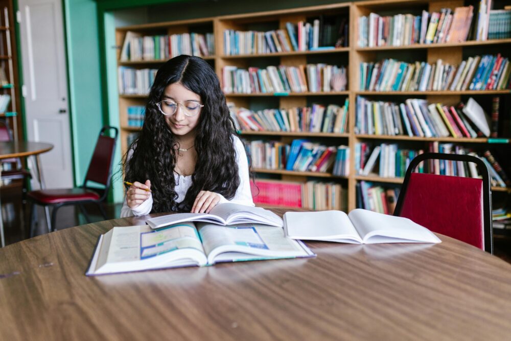 Teenage girl studying at a table in the library. (Photo by RDNE Stock project via Pexels)