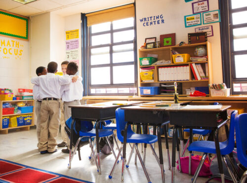 Four schoolboys (ages 8-9) huddling in classroom. (Photo by Cavan for Adobe, Adobe Stock)