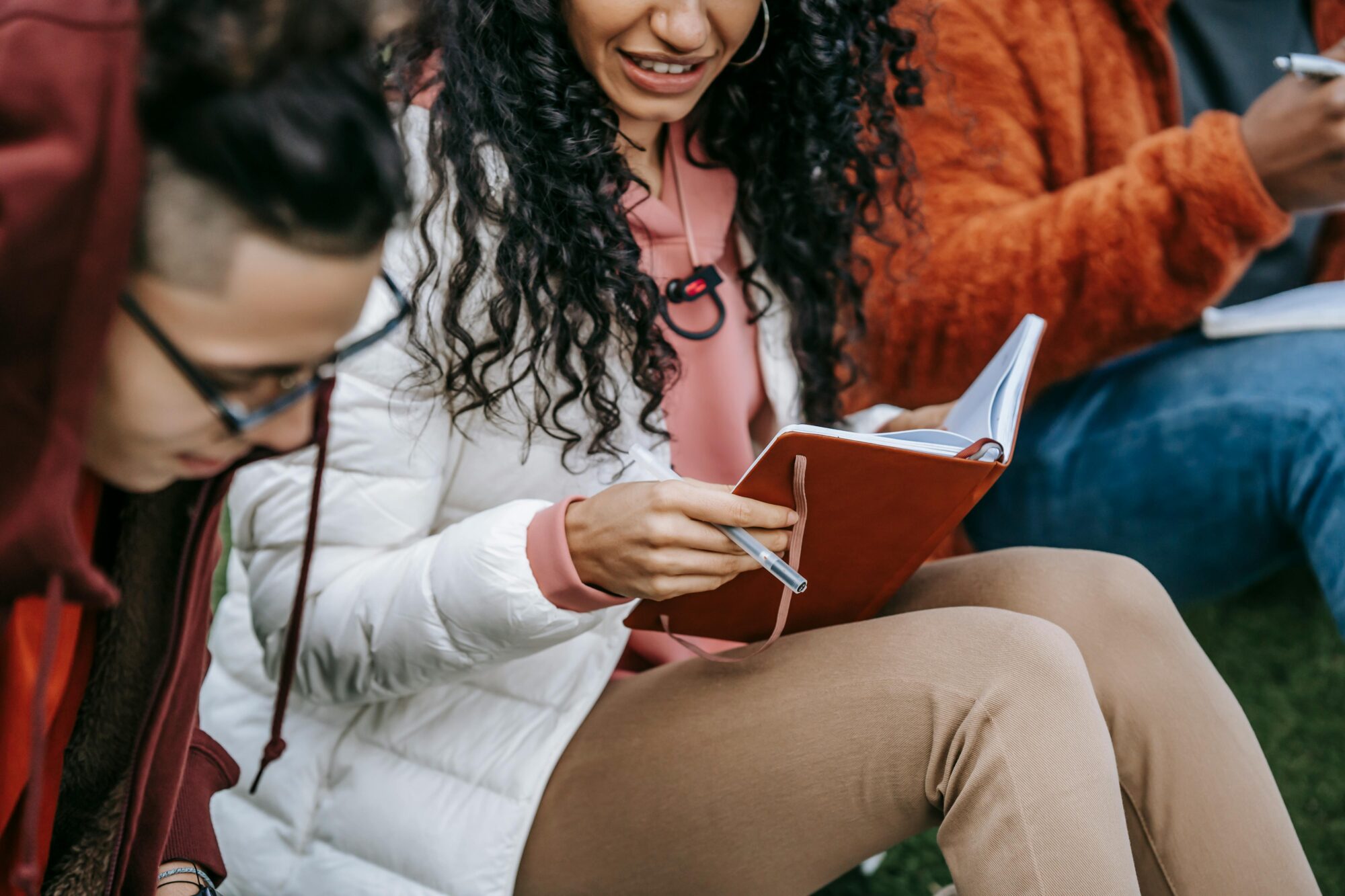 Crop of teenagers sitting outside, doing homework together. (Photo by Keira Burton from Pexels)