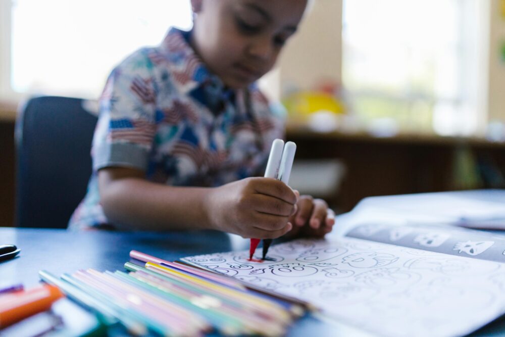 Young child colors in a coloring book. (Photo by RDNE Stock project from Pexels)