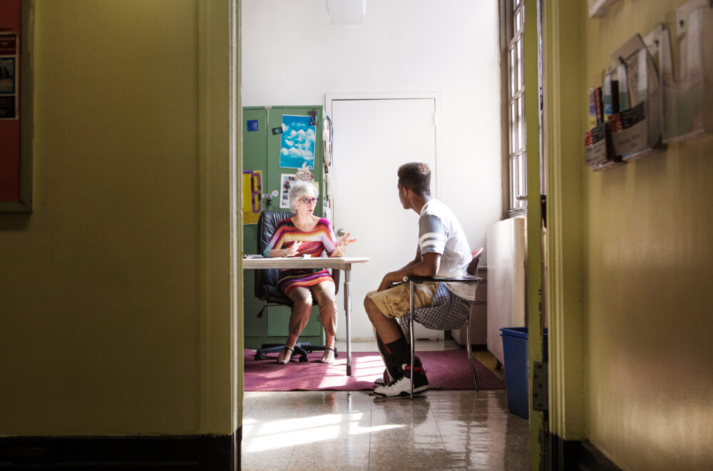 Principal talking with teenage boy while sitting in office. (Photo by Cavan for Adobe, Adobe Stock)