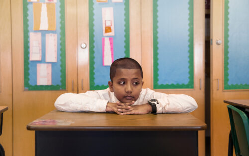 Elementary school student sitting at desk, head on hands. (Photo by Cavan for Adobe, Adobe Stock)