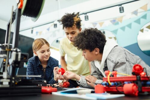 Three students in a classroom working on a technical project.