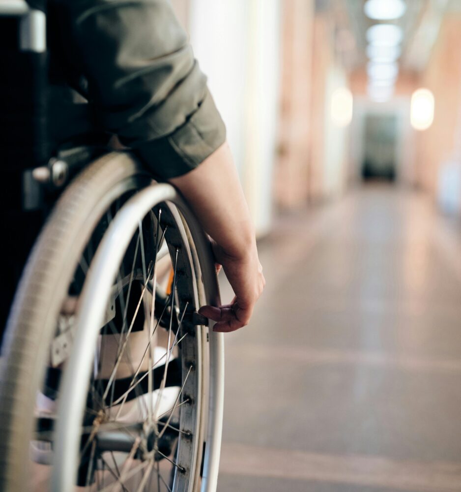 Person in a wheelchair rolls down a hallway. (Photo by Marcus Aurelius via Pexels)