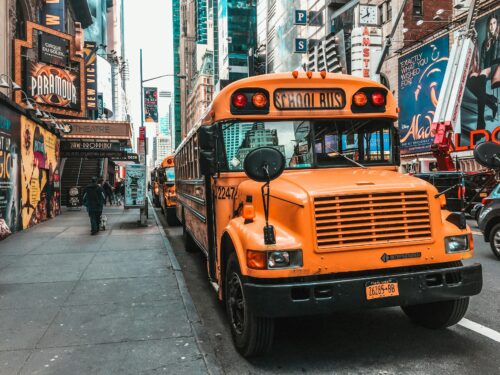 A row of school buses parked near Times Square. (Photo by Jannis Lucas on Unsplash)