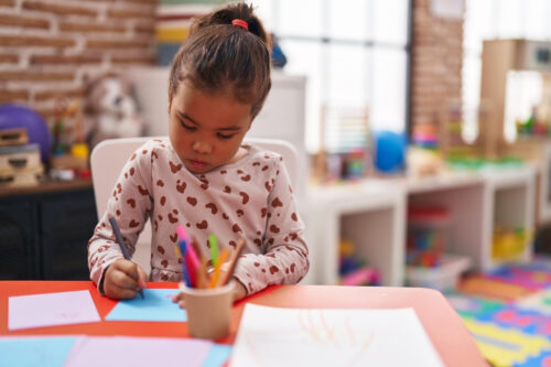 Preschool girl drawing at a table in a classroom. (Image by krakenimages.com on Freepik)