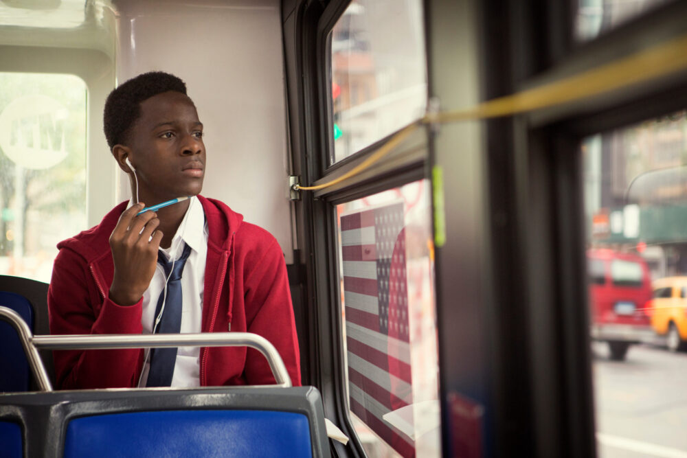 Black male teenager wearing a school uniform and riding a New York City bus.