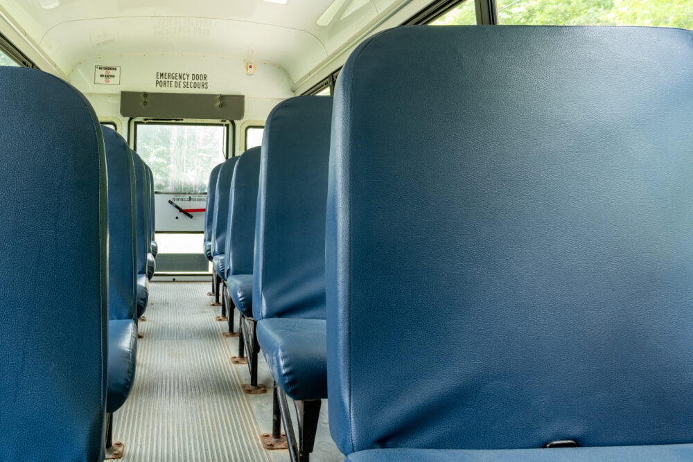 Blue seats on an empty school bus. (Photo by Roxane Bay, Adobe Stock)