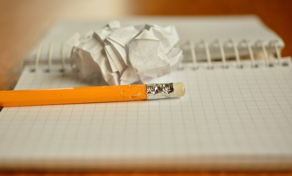 Pencil and a crumpled piece of paper resting on an open notebook. (Image by Luisella Planeta from Pixabay)