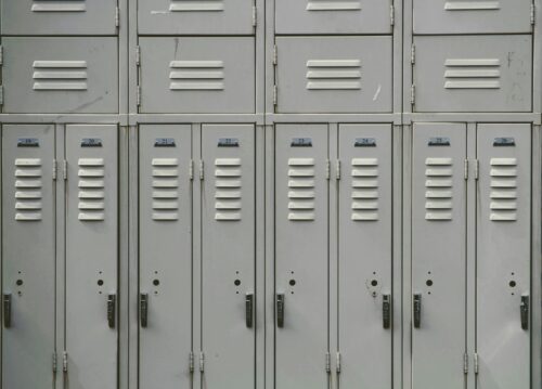 Gray lockers in a school hallway. (Photo by Joshua Hoehne on Unsplash)