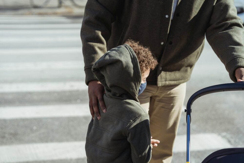 Black father touching son's shoulder on street. (Photo by Keira Burton via Pexels)