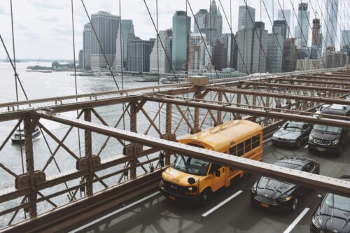 School bus driving over the Brooklyn Bridge, seen from above.