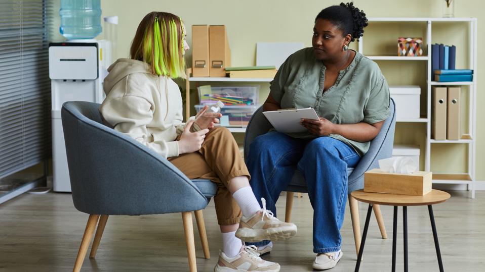 A student meets with a social worker in an office.
