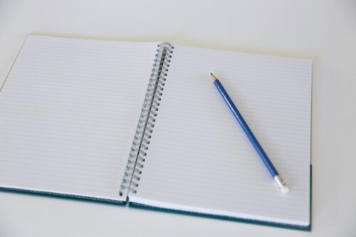 Pencil laying on an open spiral-bound notebook. (Photo by PNW Production via Pexels)