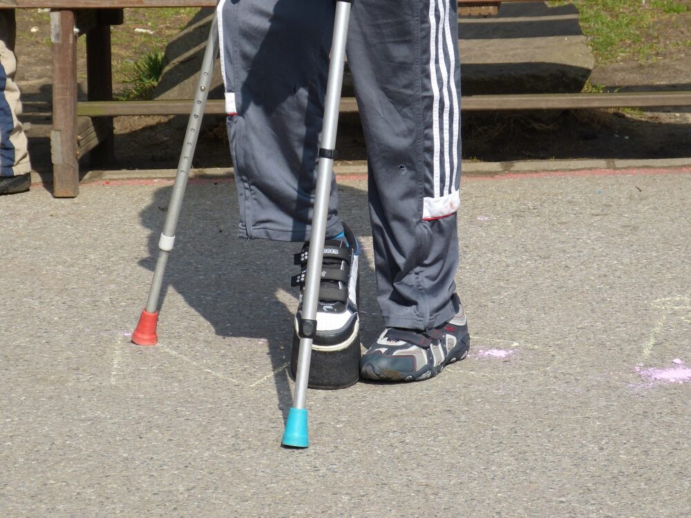 Legs of a child using crutches. (Image by falco from Pixabay)