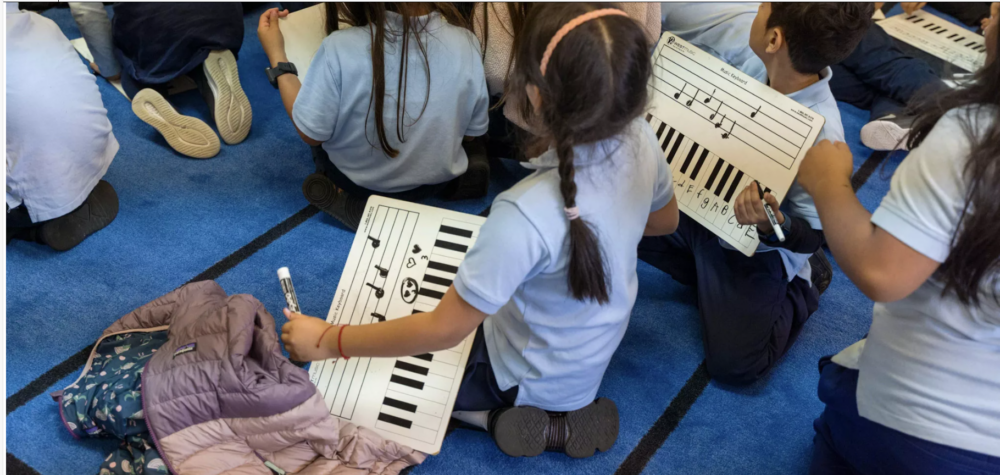 GROUP OF MIGRANT STUDENTS COMPOSING SCORES DURING MUSIC CLASS.