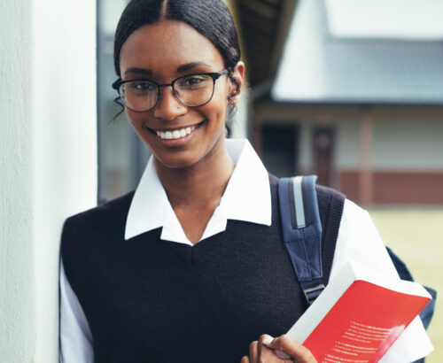 Teenage girl in school uniform holding a textbook.