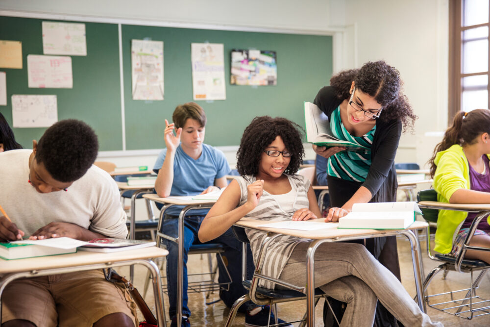 Teacher helping a high school student in a classroom. (Photo by Cavan for Adobe, Adobe Stock)