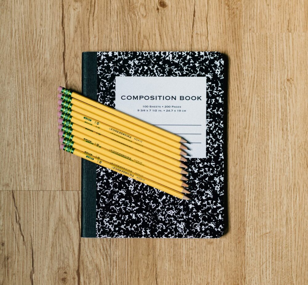 Yellow pencils on top of a black and white composition notebook. (Photo by Kelly Sikkema on Unsplash)