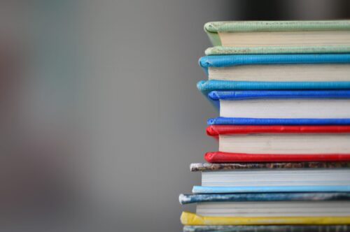 Stack of books against a blurred background. (Photo by Kimberly Farmer on Unsplash)