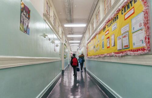 two students in backbacks in a school hallways