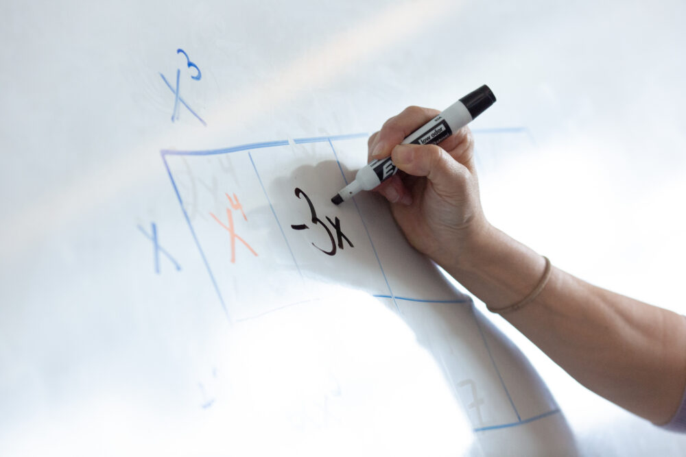 Close-up of hand on a whiteboard during a math lesson.