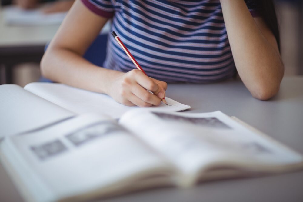 Midsection of a teenage girl studying in classroom.