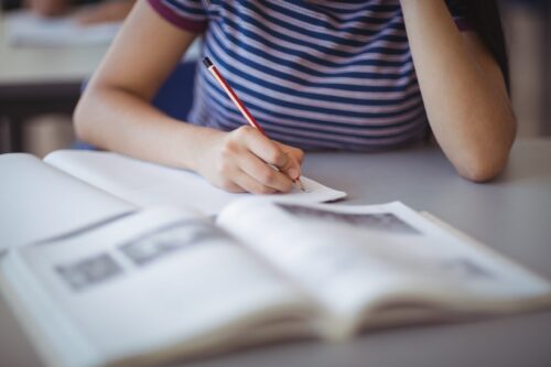 Midsection of a teenage girl studying in classroom.