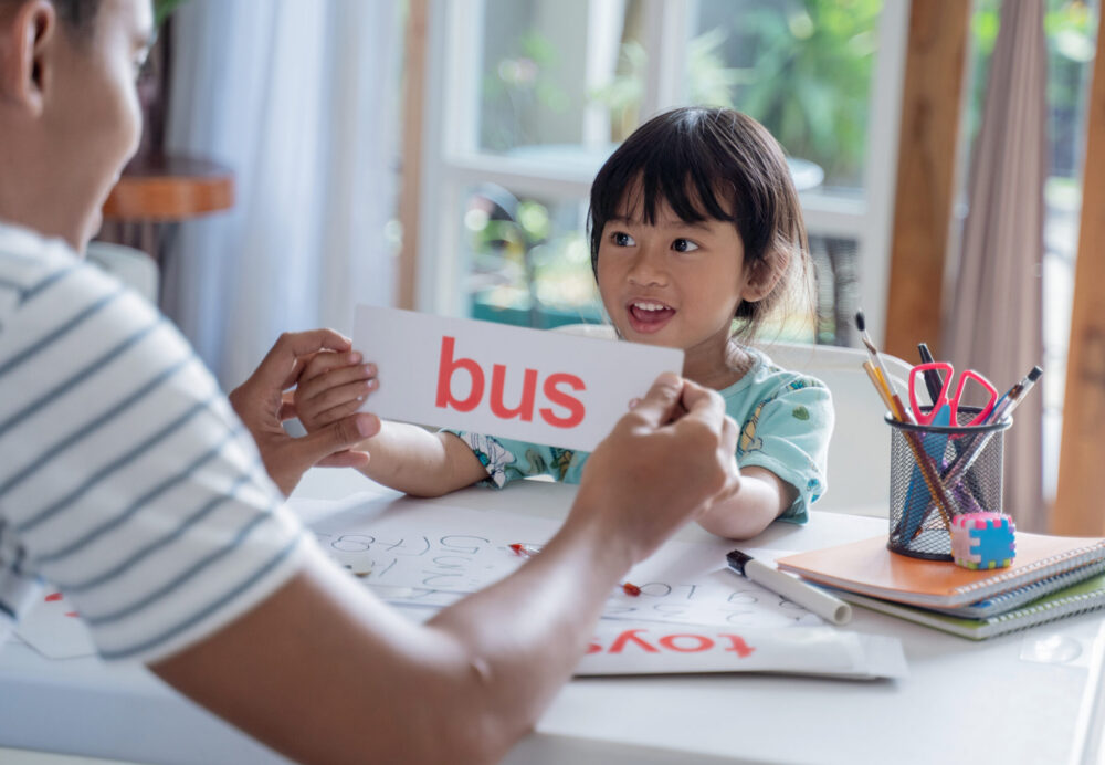 Parent showing flash card with simple word to help her daughter to read