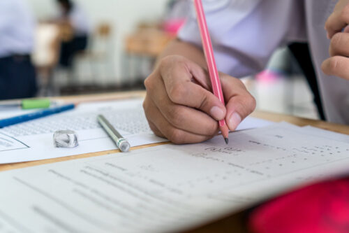 Hand of a student holding a pencil, taking a standardized exam. (Photo by smolaw11, Adobe Stock)
