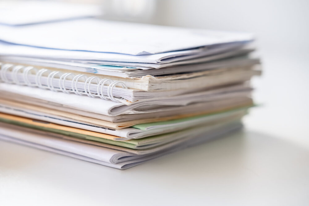 Pile of different notebooks on a white windowsill, in natural light from the window.