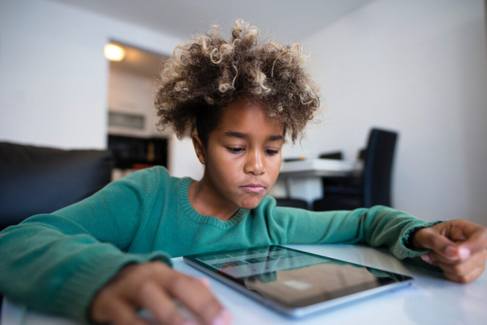 Child having online classes via tablet computer at home during the pandemic.