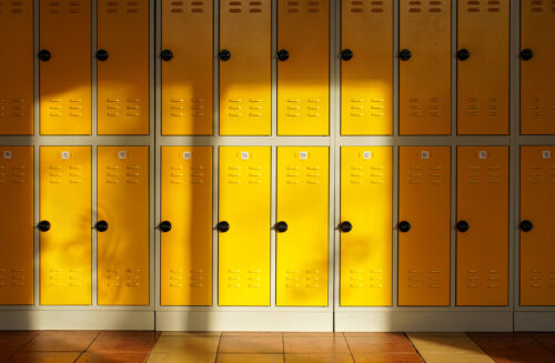 Sun shines on empty school hallway, numbered yellow lockers at the wall. (Photo by Lubo Ivanko, Adobe Stock)