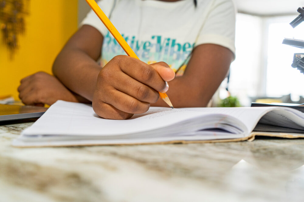 Girl writing in notebook, close up of hands