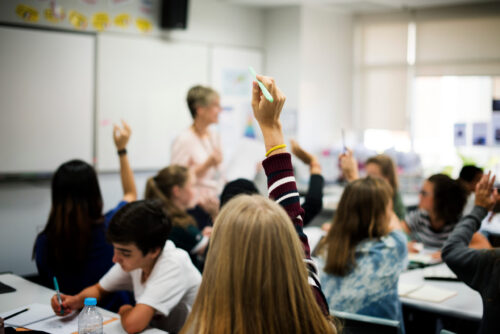 Students in the classroom raising hands