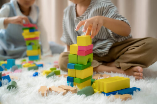 Children playing with building blocks while sitting on floor