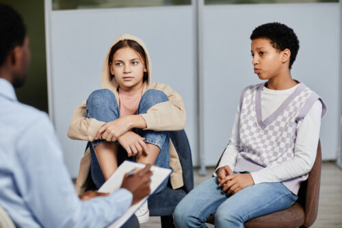 Two teenage girls speaking to psychologist in therapy session