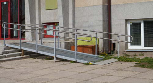 A metal ramp for wheelchairs outside entrance to a school