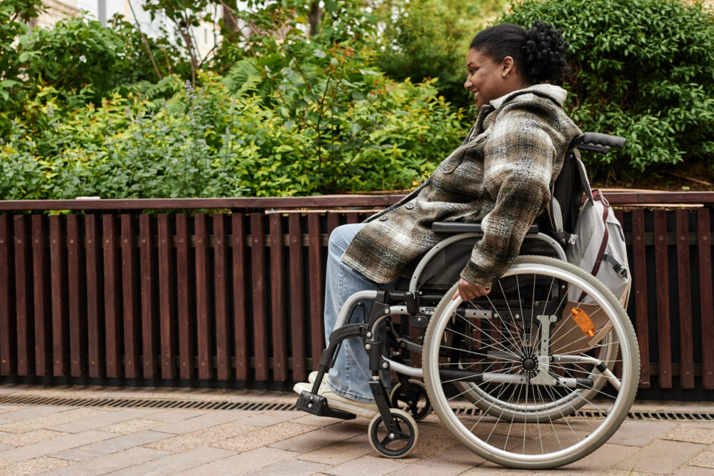 Side view portrait of smiling Black woman using a wheelchair.