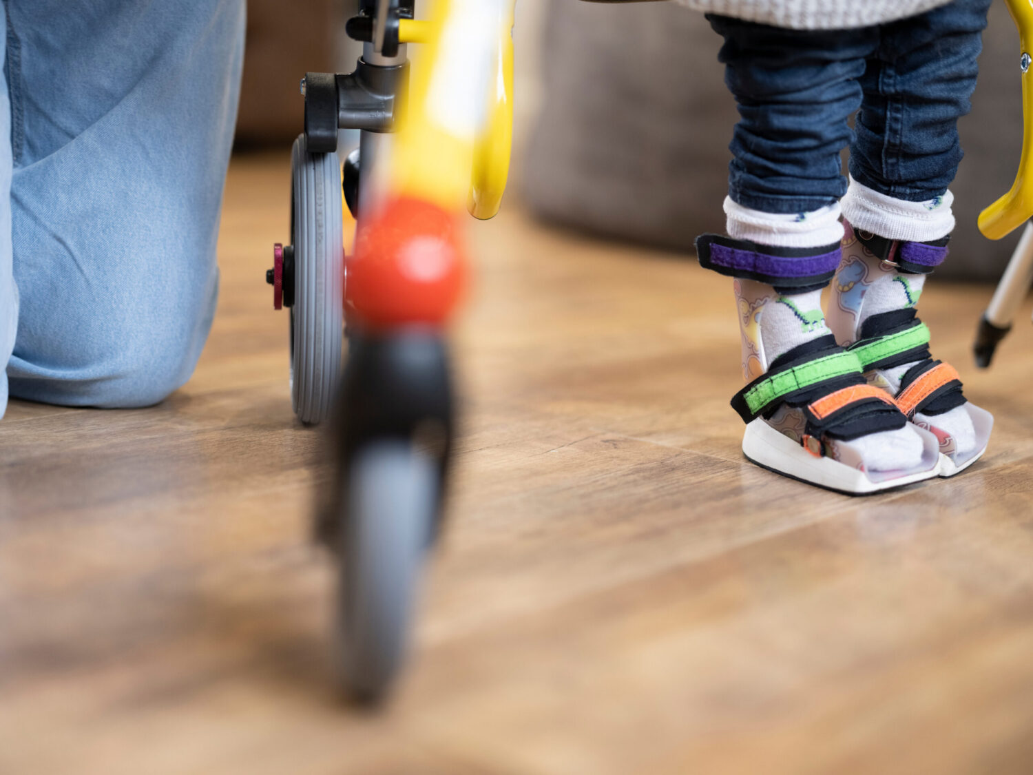 Mother kneeling next to toddler son wearing leg braces.