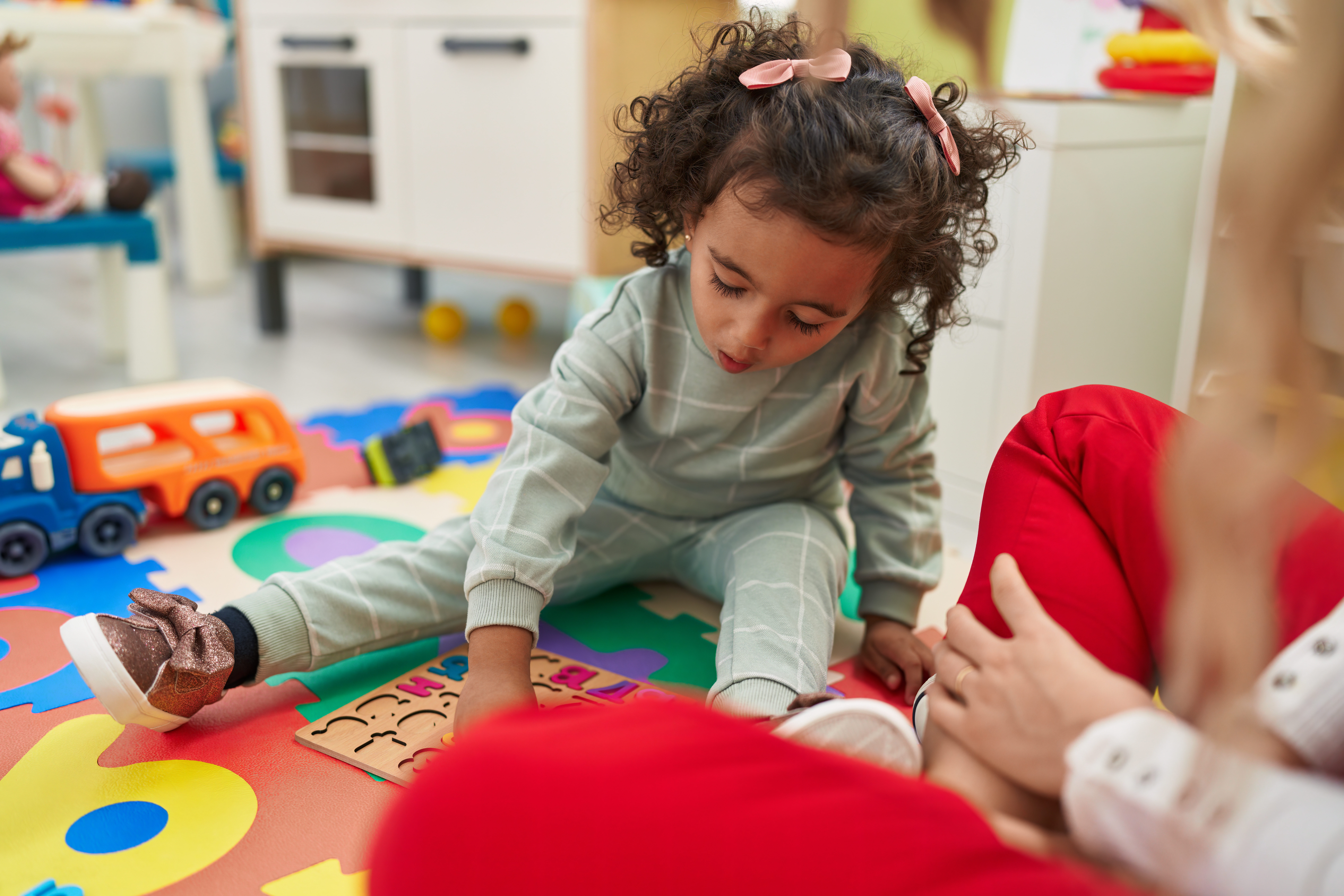 Preschool girl sitting on the floor playing a math game.