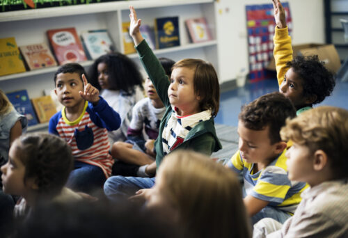 Elementary students sitting on a rug in a classroom. (Image by rawpixel.com on Freepik)