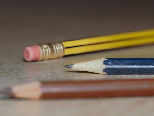 Close-up of three pencils lying on a desk.