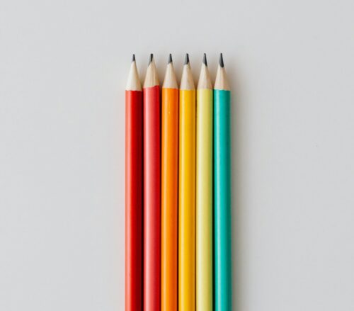 Six pencils neatly lined up in rainbow order.