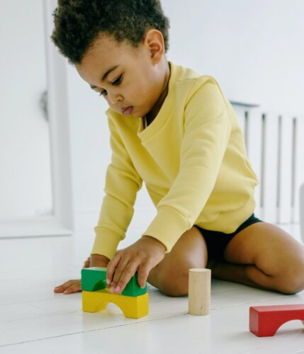 Toddler sits on the floor playing with colorful blocks.