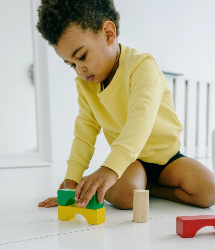 Toddler sits on the floor playing with colorful blocks.