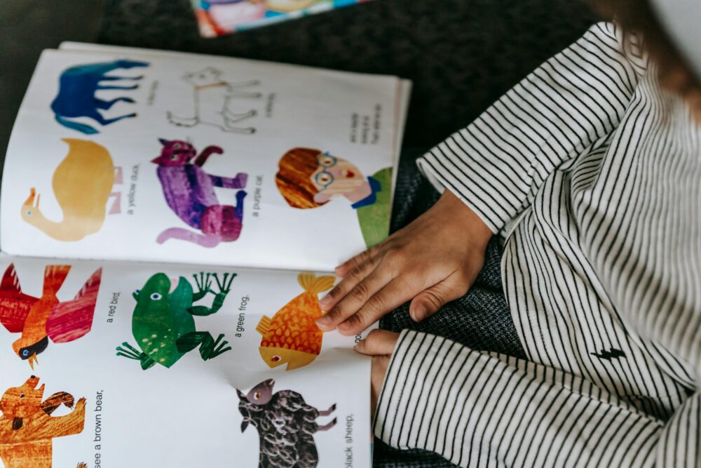Overhead shot of a child paging through a brightly colored picture book.