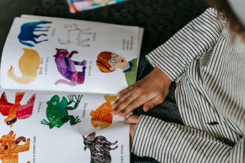 Overhead shot of a child paging through a brightly colored picture book.