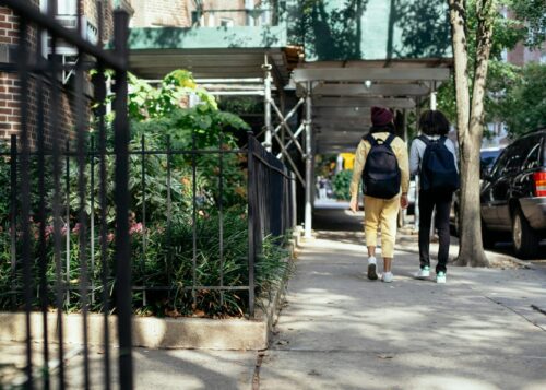 Two students walking down the street, their backs to the camera.