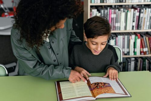 Teacher and student looking at a book in the library